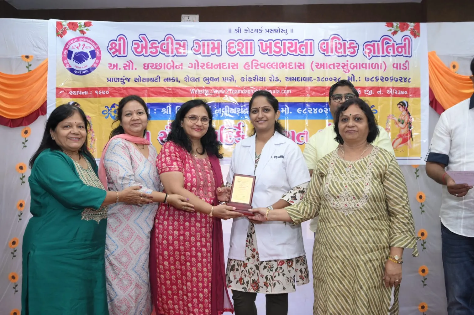 Dr. Meghna Oza receiving a commemorative plaque from community members in Ahmedabad