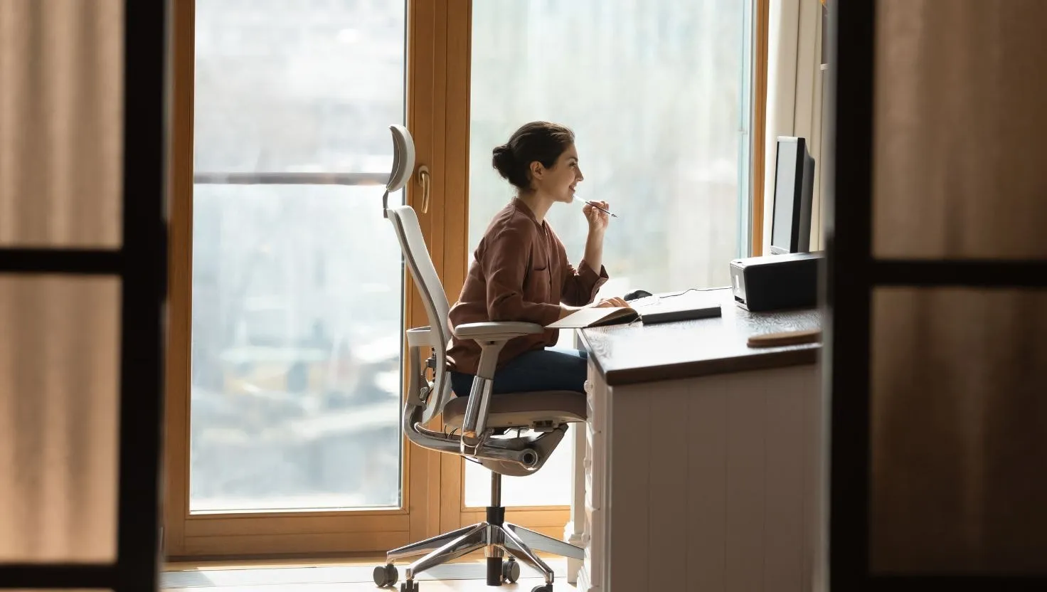 Woman working at a desk with an adjustable chair, showing good office ergonomics