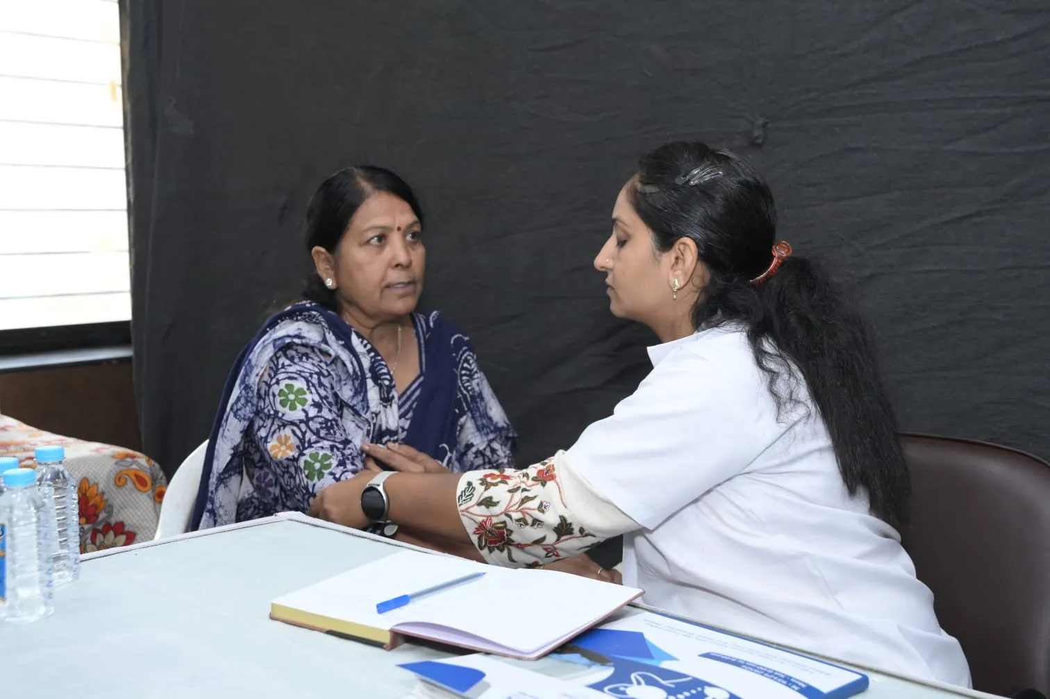 Dr. Meghna Oza reviewing case papers at her desk during a consultation