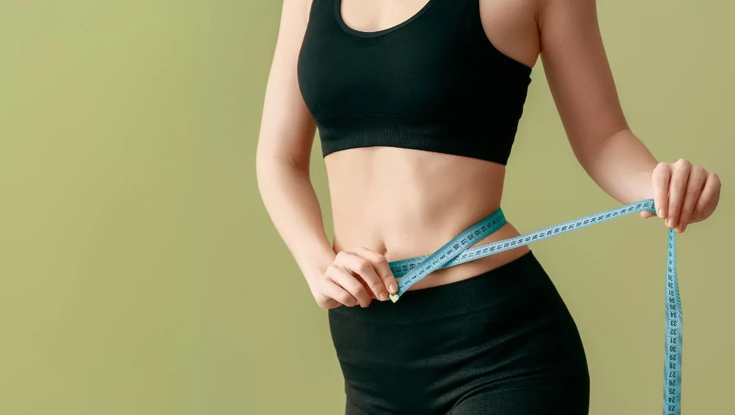 Woman measuring her waist with a measuring tape